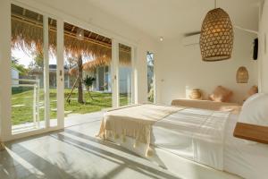 a white bedroom with a bed and a large window at The Bingin Beach Villas' Bungalow Resort in Uluwatu