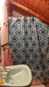 uma casa de banho com um lavatório e uma cortina de chuveiro em Hostal La Casa del Carpintero em Coñaripe