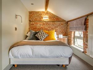 a bed in a room with a brick wall at The Ingham Swan in Stalham