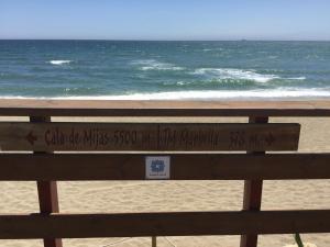 a bench at the beach with a sign on it at Macdonald Leila Playa Resort in La Cala de Mijas
