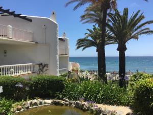 a building with palm trees and the ocean in the background at Macdonald Leila Playa Resort in La Cala de Mijas