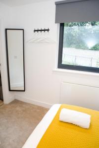 a bedroom with a yellow bed and a mirror at Pres Pier Apartment - Bournemouth in Bournemouth