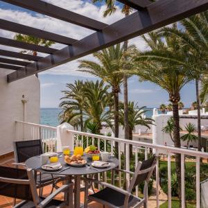 a table and chairs on a balcony with the ocean at Macdonald Leila Playa Resort in La Cala de Mijas