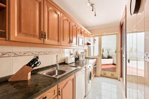 a kitchen with wooden cabinets and a sink at Macdonald Leila Playa Resort in La Cala de Mijas
