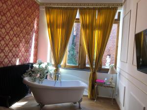 uma banheira num quarto com cortinas amarelas em Love Nest Versailles - Unique Louis XIV decoration - Calm location right IN city center em Namur