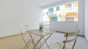 a table and chair on a balcony with a white wall at Italianway - Ottoventi Apartments in Lampedusa