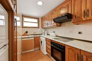 a kitchen with wooden cabinets and a sink and a dishwasher at Macdonald Leila Playa Resort in La Cala de Mijas