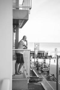 un homme debout sur un balcon d'un bâtiment dans l'établissement Carpe diem Noguchi 201- Adults Only, à Saint-Idesbald