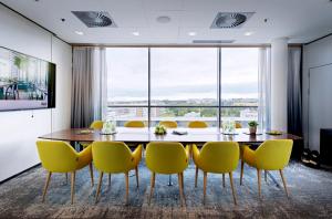 a dining room with a table and yellow chairs at GLO Hotel Sello in Espoo