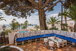 a blue couch on a patio with a tree at Macdonald Leila Playa Resort in La Cala de Mijas