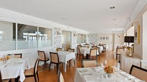 a dining room with white tables and chairs at Macdonald Leila Playa Resort in La Cala de Mijas