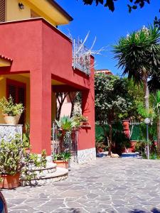 un bâtiment rouge avec des plantes devant lui dans l'établissement Casa vacanze Isolotto, à Isola delle Femmine