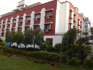 a large red and white building with trees and plants at Hotel Siddharth in Varanasi