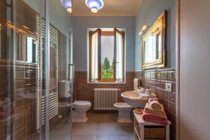 bagno con lavandino, servizi igienici e finestra di Agriturismo Villa Ulivello in Chianti a Strada