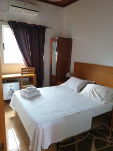 Un dormitorio con una cama con sábanas blancas y una ventana. en Residencial Mira Rio, en Santo António