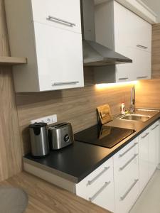a kitchen with white cabinets and a black counter top at Bervia Apartman in Szombathely +5 photos