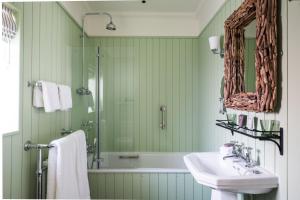 a green bathroom with a tub and a sink at The Swan Hotel in Southwold