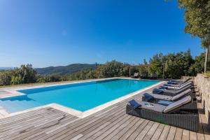 a swimming pool with lounge chairs next to a wooden deck at Villa Casenovole in Murlo