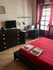 Schlafzimmer mit einem roten Bett und einem Schreibtisch in der Unterkunft Casa Delfino - Appartamento Centro Storico a due passi dalla Spiaggia & Mare, Porto & Ferrovia in Civitavecchia