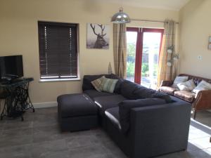 a living room with a couch and a tv at Three Peaks View Cottage in Wigglesworth