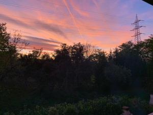 una puesta de sol con una torre de transmisión de electricidad y árboles en Aurelia Rta Detta il Cascinale, en Montignoso