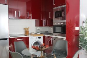 a kitchen with red cabinets and a glass table with chairs at Apartamento Homelife Roca Tarpeya 4 in Toledo