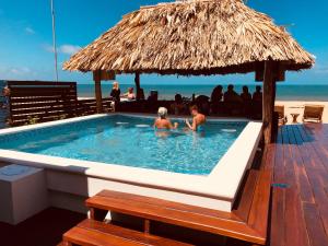two people in a swimming pool with a straw umbrella at Ocean Breeze in Placencia Village