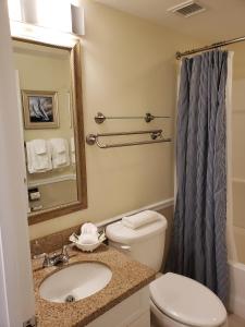 a bathroom with a sink and a toilet and a mirror at The Cove at Yarmouth, a VRI resort in Yarmouth