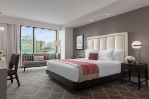 a bedroom with a large bed and a living room at Hotel Commonwealth in Boston