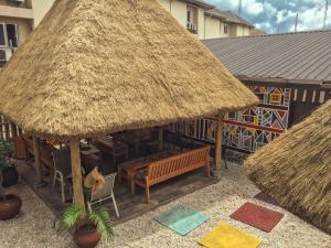 ein Restaurant im Freien mit einer Bank und einem Strohdach in der Unterkunft Visa Karena Hotels in Port Harcourt
