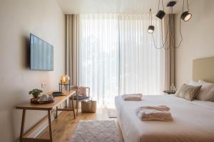 a bedroom with a bed and a desk and a window at Aroeira Lisbon Hotel - Sea & Golf in Aroeira