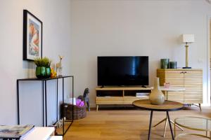 ein Wohnzimmer mit einem Flachbild-TV und einem Tisch in der Unterkunft Modern Appartment in the Heart of Ghent in Gent