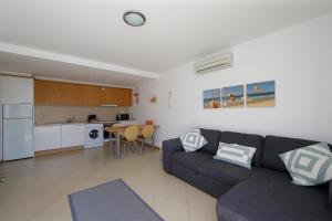 a living room with a couch and a kitchen at Apartamento Laranjas Garden in Cabanas de Tavira