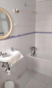 ein Badezimmer mit einem Waschbecken, einer Badewanne und einem Spiegel in der Unterkunft PENSIÓN LARRA in Mairena del Alcor