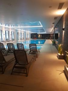una piscina en un hotel con sillas en el vestíbulo en Apartament Bałtyk Nadmorskie Tarasy z parkingiem, en Kołobrzeg
