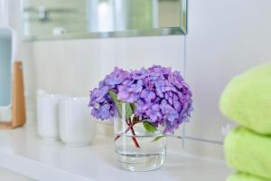 Bosbüll的住宿－Ferienwohnungen Bosbuell Huus，花瓶装紫色花,坐在柜台上
