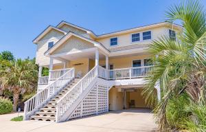 a large yellow house with white stairs and palm trees at Show Boat in Kitty Hawk