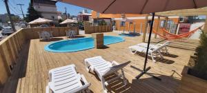 a deck with chairs and an umbrella and a pool at Pousada Milani in Florianópolis