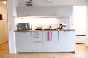 cocina con armarios blancos y encimera en Outletcity Apartment Ferienwohnung Metzingen, en Metzingen