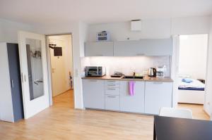 cocina con armarios blancos y encimera en Outletcity Apartment Ferienwohnung Metzingen, en Metzingen