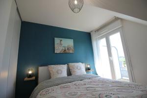 a bedroom with a bed with a blue wall at Gite - Le Toucan - Maison avec Terrasse dans parc avec piscine proche plages et Golf in Pléneuf-Val-André