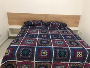a bed with a colorful quilt and pillows on it at Praia do Frances in Praia do Frances