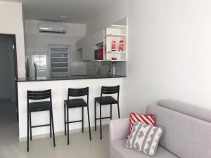 a living room with a couch and a bar with stools at Praia do Frances in Praia do Frances