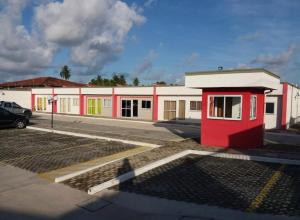 a building with a red door in a parking lot at Praia do Frances in Praia do Frances