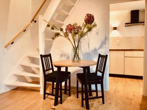 een tafel met twee stoelen en een vaas met bloemen bij Cala Bassa Beachhouse in Noordwijk aan Zee