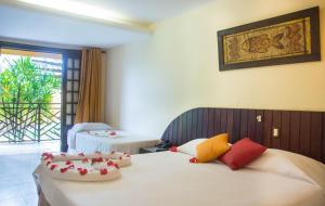 a hotel room with two beds with red and yellow pillows at Hotel Aconchego Porto de Galinhas in Porto De Galinhas +71 photos