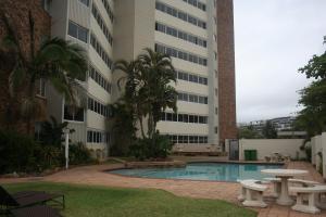 a building with a pool and picnic tables in front of it at 71 Sea Lodge Beachfront Apartment in Durban