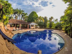 a swimming pool in a resort with palm trees at Hotel Hacienda Gualanday in Villavicencio