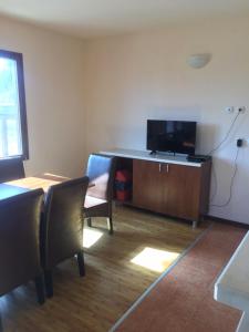a living room with a television and a table and chairs at Вилно селище Баташки хан in Tsigov Chark