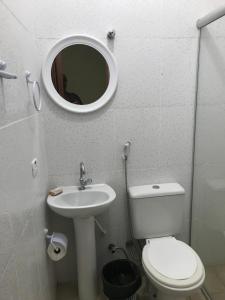 ein Badezimmer mit Toilette, Waschbecken und Spiegel in der Unterkunft Suites em Maresias in Maresias + 15 Fotos